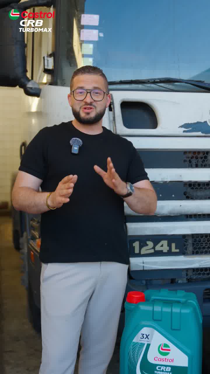 A man speaking to camera beside a white truck cab, a green Castrol CRB Turbomax container in front of him.