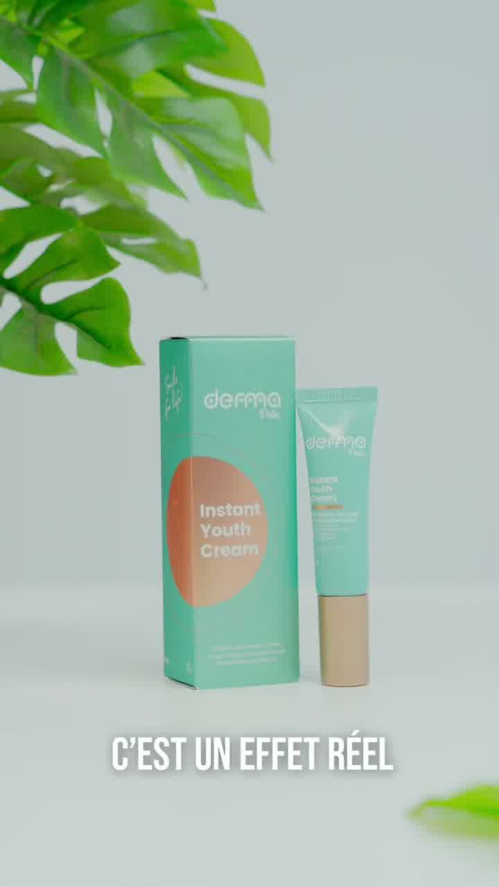 A mint green carton and tube of Instant Youth Cream on a white surface beside a monstera leaf, with the line “c’est un effet réel”.