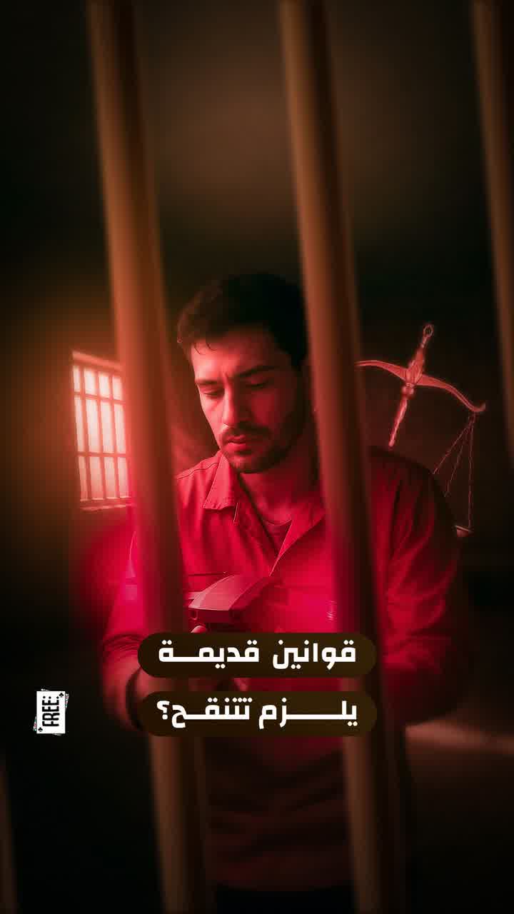 A man behind prison bars under red light, with an Arabic caption about outdated laws.