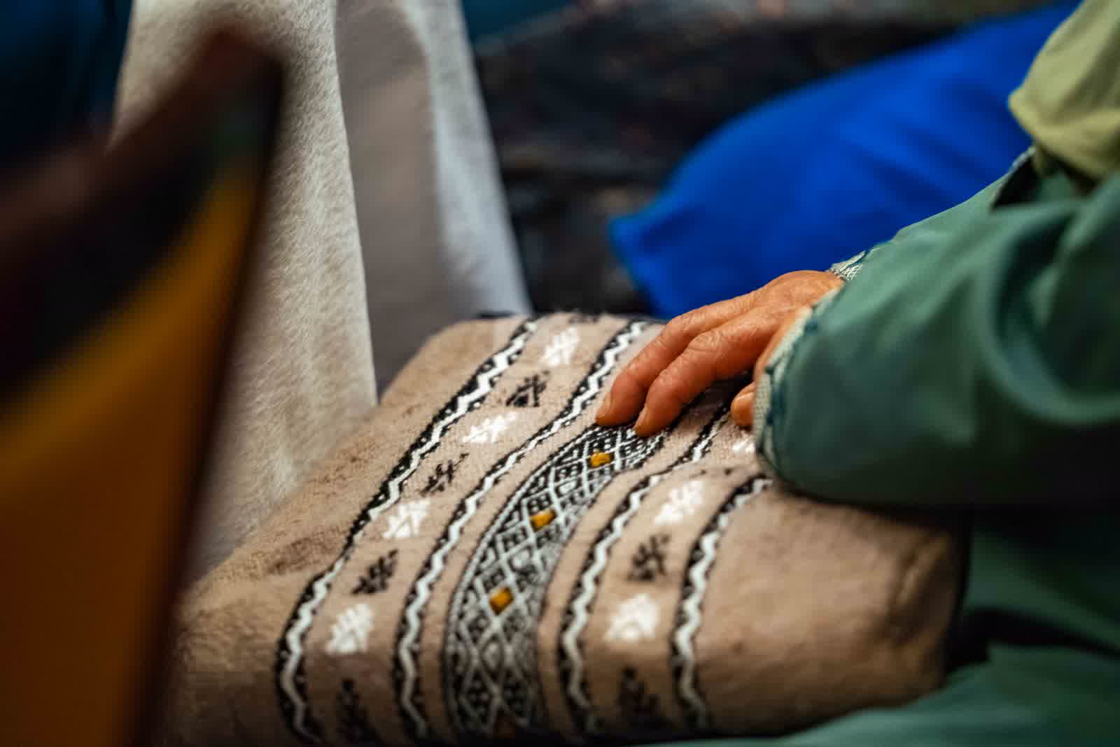 Close-up of an embroidered sleeve and a pair of hands resting together.