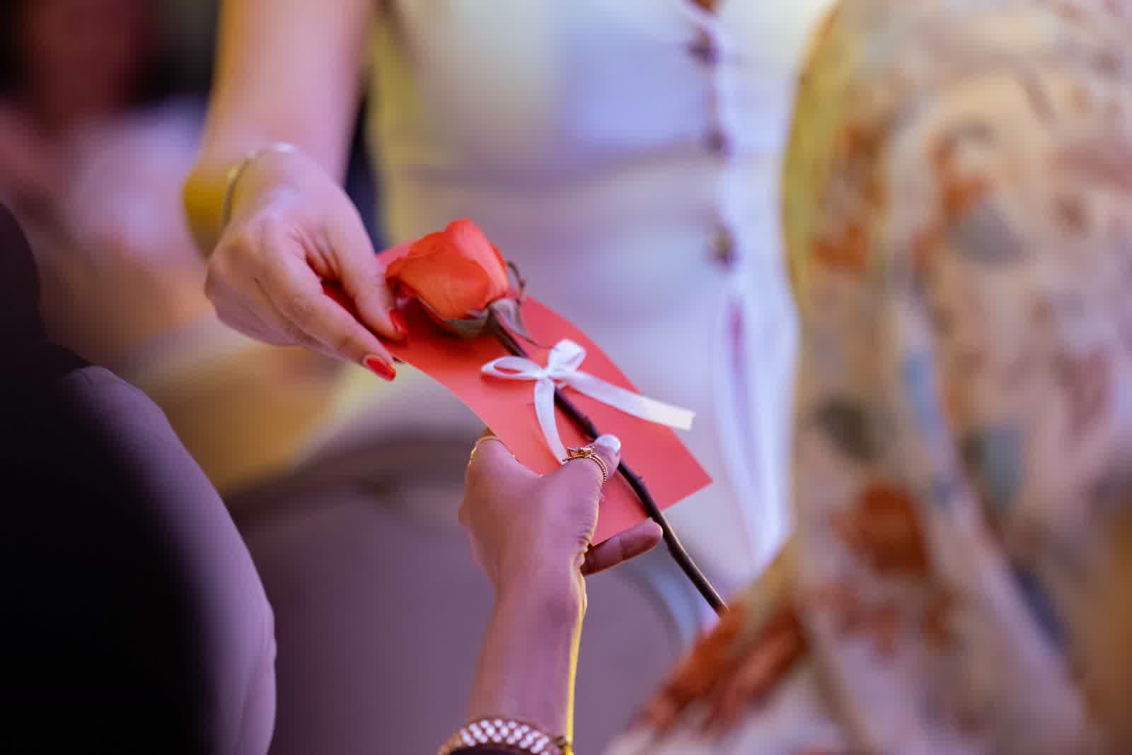 Hands tying a red ribbon around a small gift.