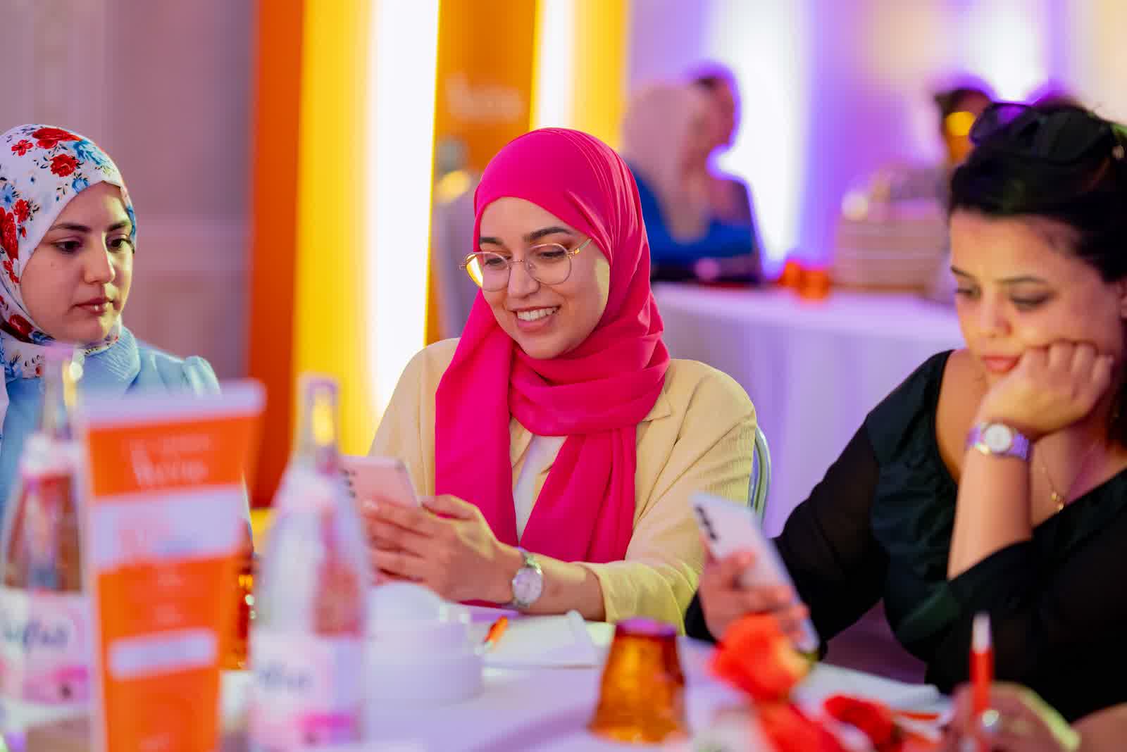 Guests seated around a table at an event, the room lit in pink.